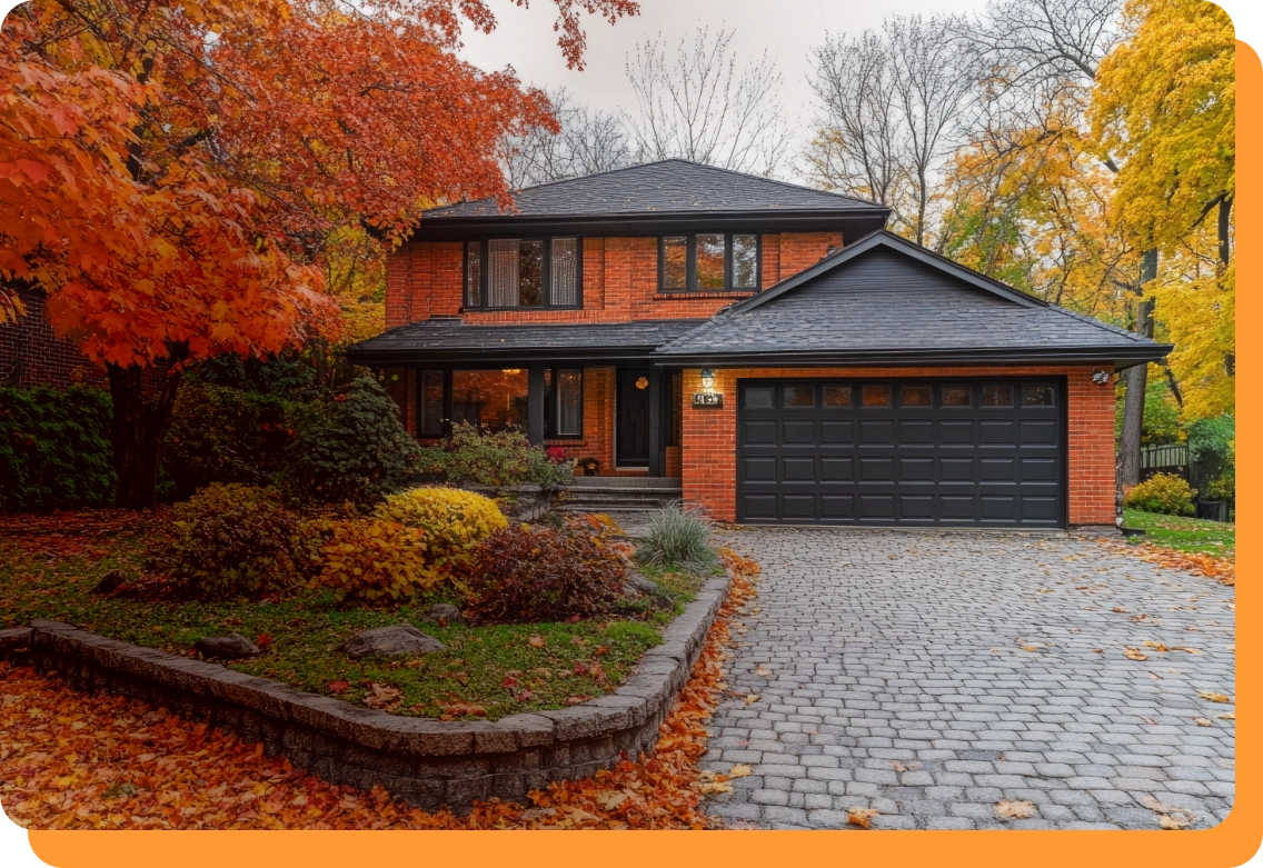 Brick Colorado Springs home with fall foliage, a stone-edged garden bed and paver driveway