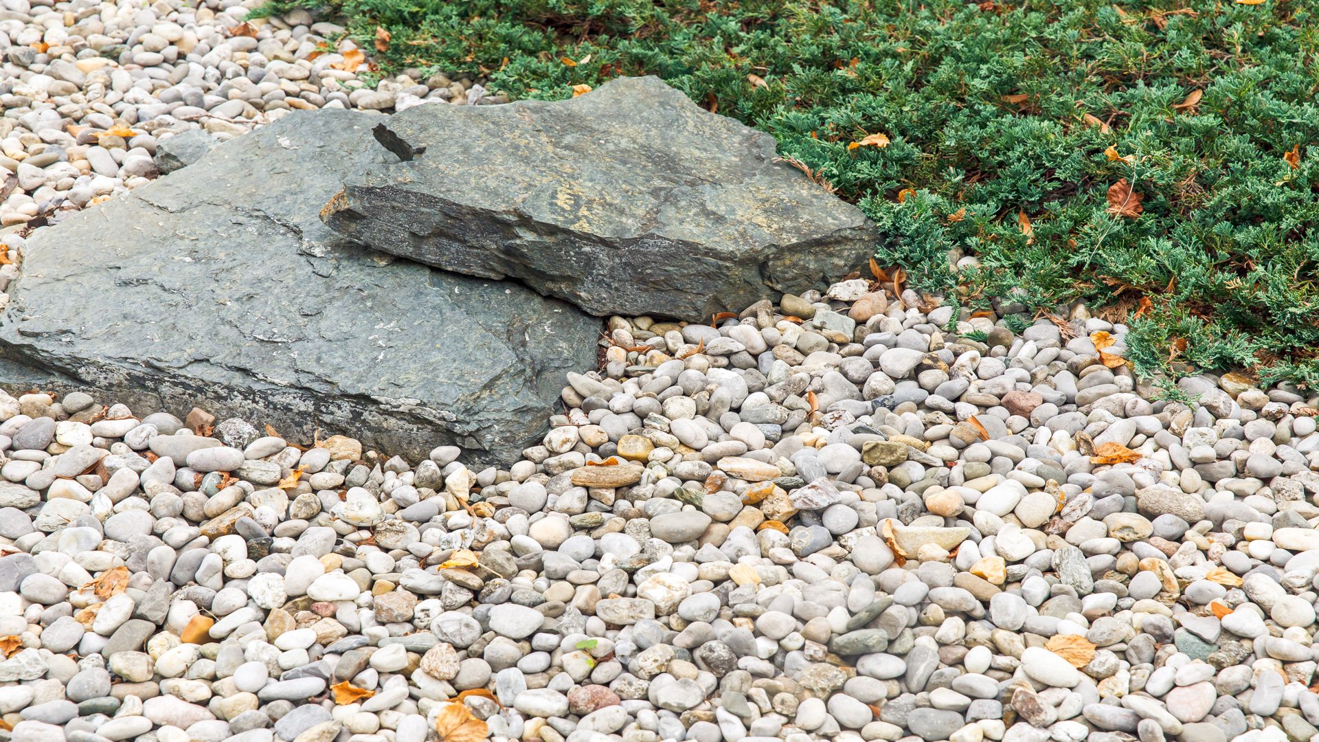 Natural garden scene with large rocks, pebbles, and green plants, perfect for landscape design concept Artificial Turf for Colorado Springs Yards